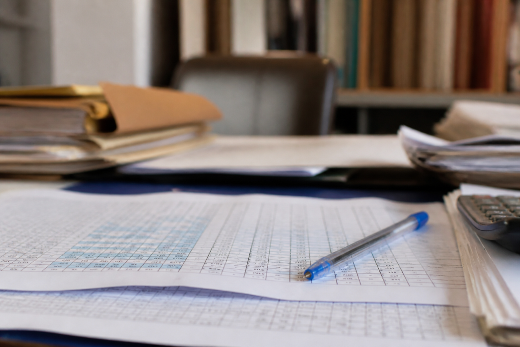Tableau avec calculs cotisations sociales, stylo bleu, documents financiers