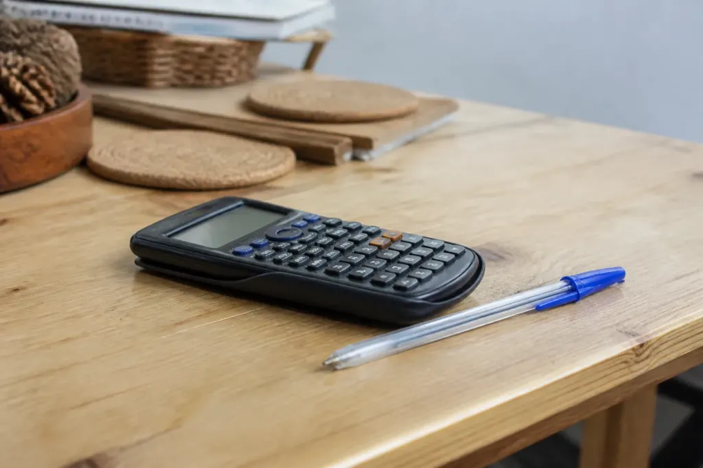 Calculatrice et stylo posés sur un bureau en bois