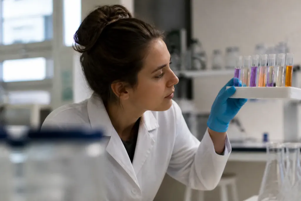 Jeune chercheuse observant des tubes colores dans un laboratoire